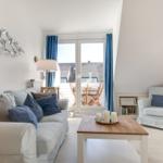 Wohnzimmer mit Sofa, Sessel und Balkonansicht.