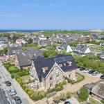 Haus mit Solaranlage, umgeben von Grün und Strand