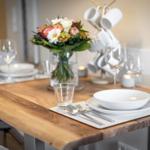 Dining table with plates, glasses, and flower arrangement.