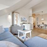 Living and dining area with sofa, table, and chairs. Wooden floor and white furniture.