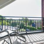 Terrace with lounge chair and flower basket. View of green surroundings and rooftops.