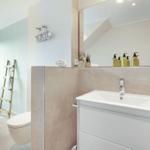 Bathroom with sink, mirror, toilet, and window