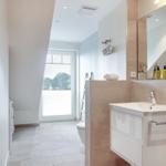 Bathroom with sink, mirror, shower, and window.
