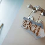 Wooden sign with the word Beach hangs on chrome hooks on the wall.