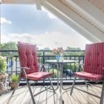 Terrace with two chairs, table, and plants. View of green surroundings.