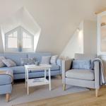 A living room with blue sofa, gray armchair and wooden floor. Against the wall is a cabinet with glass doors.