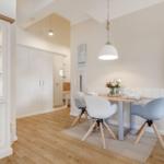 Dining area with table, chairs, and wall art. Wooden floor and white cabinet.