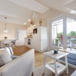 Living room with kitchen and balcony. Modern furnishings and wooden floor.