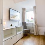 Schlafzimmer mit TV, Stuhl und Fenster