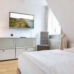 Schlafzimmer mit Bett, Fernseher und Fenster