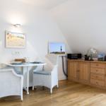 Essbereich mit Tisch, zwei Stühlen und Holzschrank an geneigter Wand.