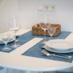 Tisch mit Platzierung für zwei Personen, blauen Tischdecken und Gläsern.