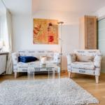 Wohnzimmer mit Sofa, Sessel und Glas-Tisch auf Teppich
