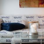 Sofa mit nautischem Muster, Kissen und brennender Kerze.