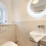 Badezimmer mit Waschbecken, Spiegel und Fenster