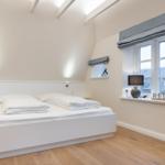 Schlafzimmer mit Doppelbett, Holzboden und Fenster mit Blick.