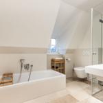 Bad mit Badewanne, Dusche und Toilette unter Dachschrägen.