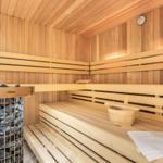 Sauna mit Holzbänken, Steinkessel und Holzschale.