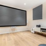 Großer Home Cinema Raum mit Projektionswand und modernem Audio-Setup.