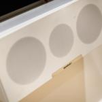 Weißer Lautsprecher mit drei runden Membranen an der Wand
