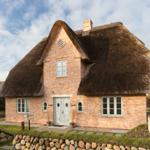 Haus mit strohgedecktem Dach und Backsteinfassade