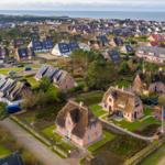 Dorf mit strohgedeckten Häusern und Blick aufs Meer