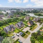 Aerial view of houses with gardens and a lake in an urban area.