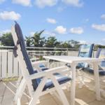 Terrace with white chairs and table under blue sky.