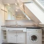 Washroom with washing machine and mirror cabinet under sloped roof.