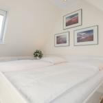 Bedroom with double bed, window, and wall pictures.
