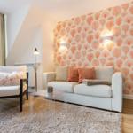 Living room with sofa, armchair, and orange patterned wallpaper on the wall.