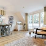 Living and dining area with wooden floor, windows, and furniture.