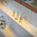 Sink with faucet and toiletries on white tiled wall.