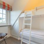 Room with bunk bed, window, and chair with pillow.