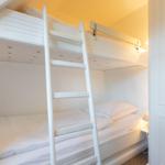 A bedroom with two white bunk beds and a ladder.