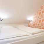 Bedroom with white bed and orange patterned wall covering.