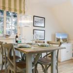 Dining room with wooden table, chairs, and window overlooking trees.