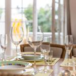 Table with plates, glasses, and cutlery on yellow placemats.