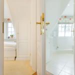 Bedroom and bathroom with sloped ceilings and white walls.