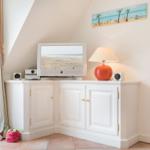 TV on white cabinet, lamp and beach picture on wall