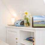 White cabinet with radio, flowers, and brochures in attic room.