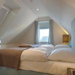 Bedroom with sloped ceiling, bed, window, and TV.