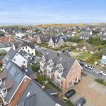 Aerial view of a residential area near the sea with houses and parked cars.