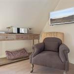 A room with a chair, a desk, and a wall-mounted TV unit.