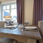 Dining table with chairs, table setting, and windows with curtains.