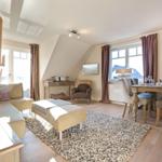 Living and dining area with sofa, table and chairs. Wooden floor and large windows.