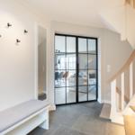 Eingang mit Bank, Garderobe und Blick in Wohnbereich über Glaswand.