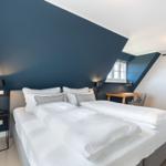 Schlafzimmer mit Doppelbett, blauer Wand und Schreibtisch