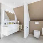 Moderne Dusche, Waschbecken und Toilette in einem geräumigen Badezimmer mit schrägen Wänden.