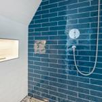 Dusche mit blauen Fliesen und eingebauter Ablage